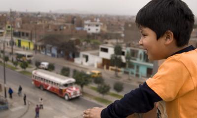 little boy looking out over a city from a balcony 