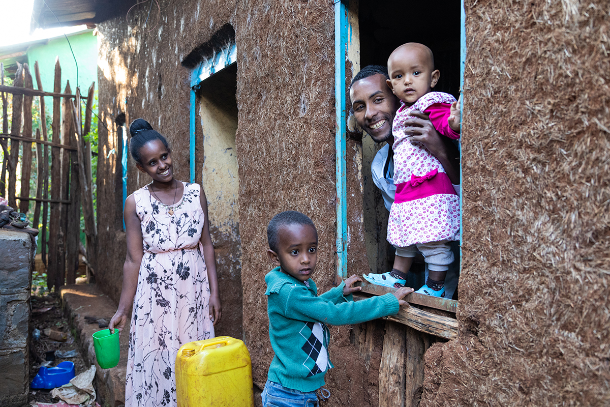 Family standing by the house with two young children