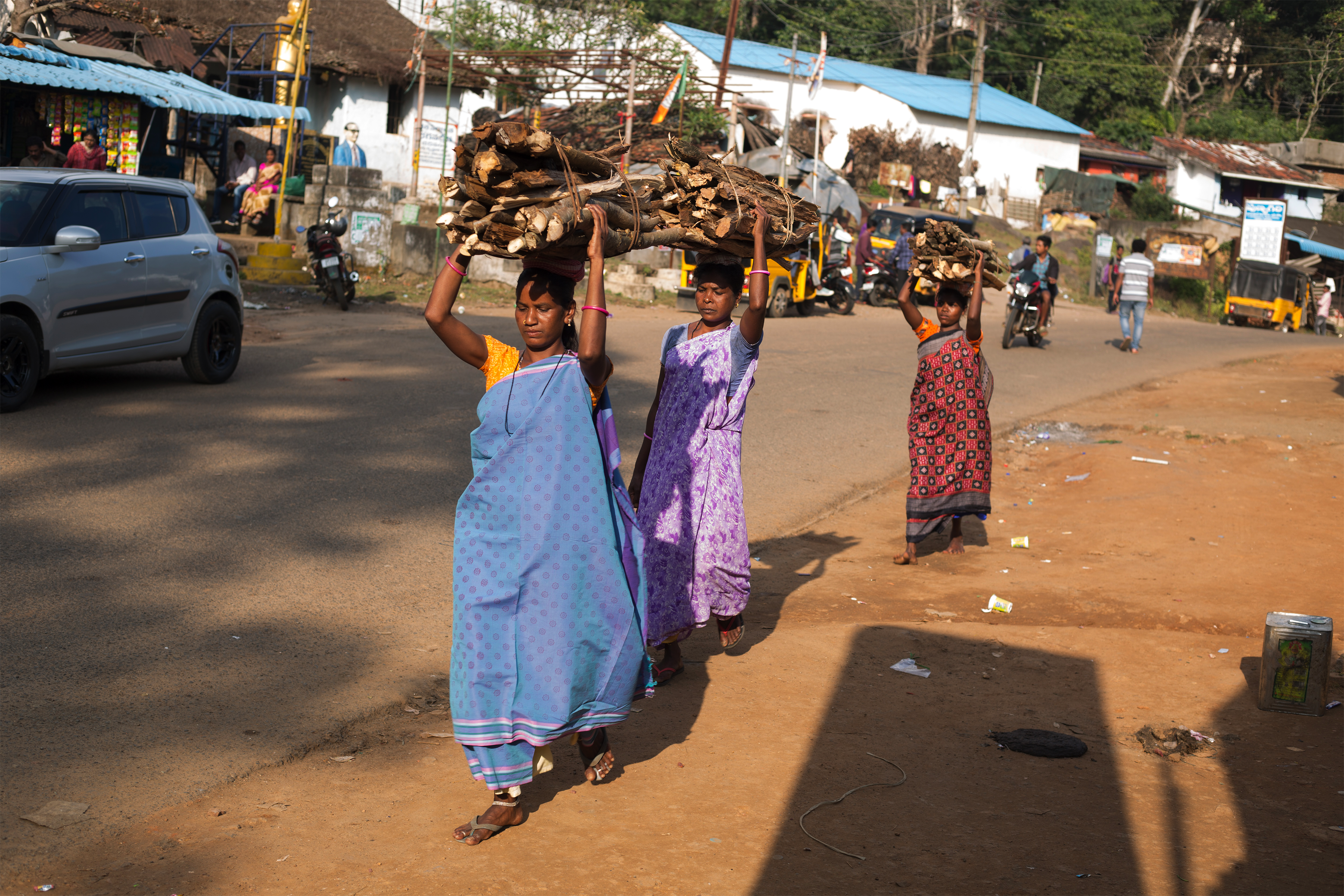 Three women carrying logs on their head