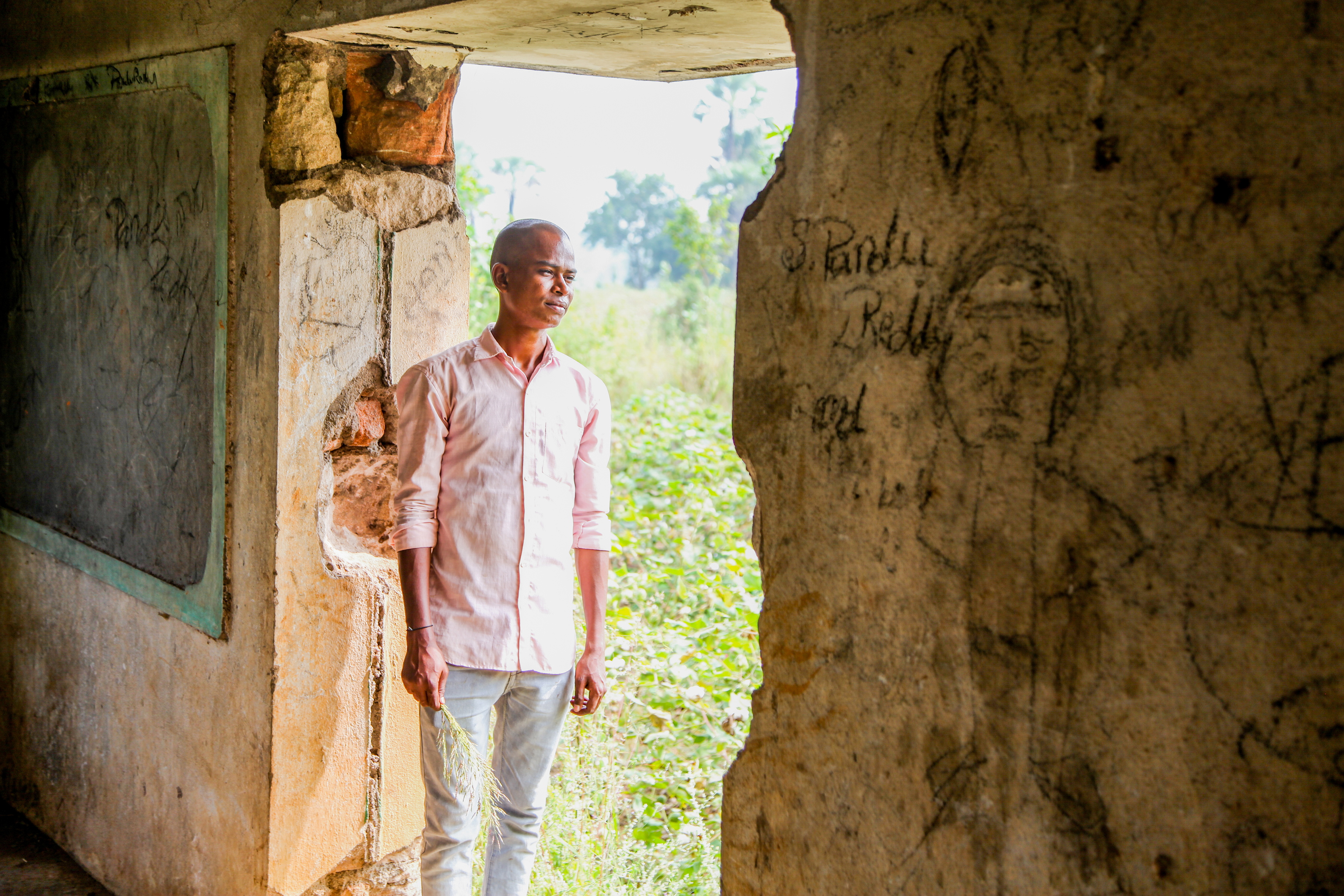 Young man outside rural home looking into distance