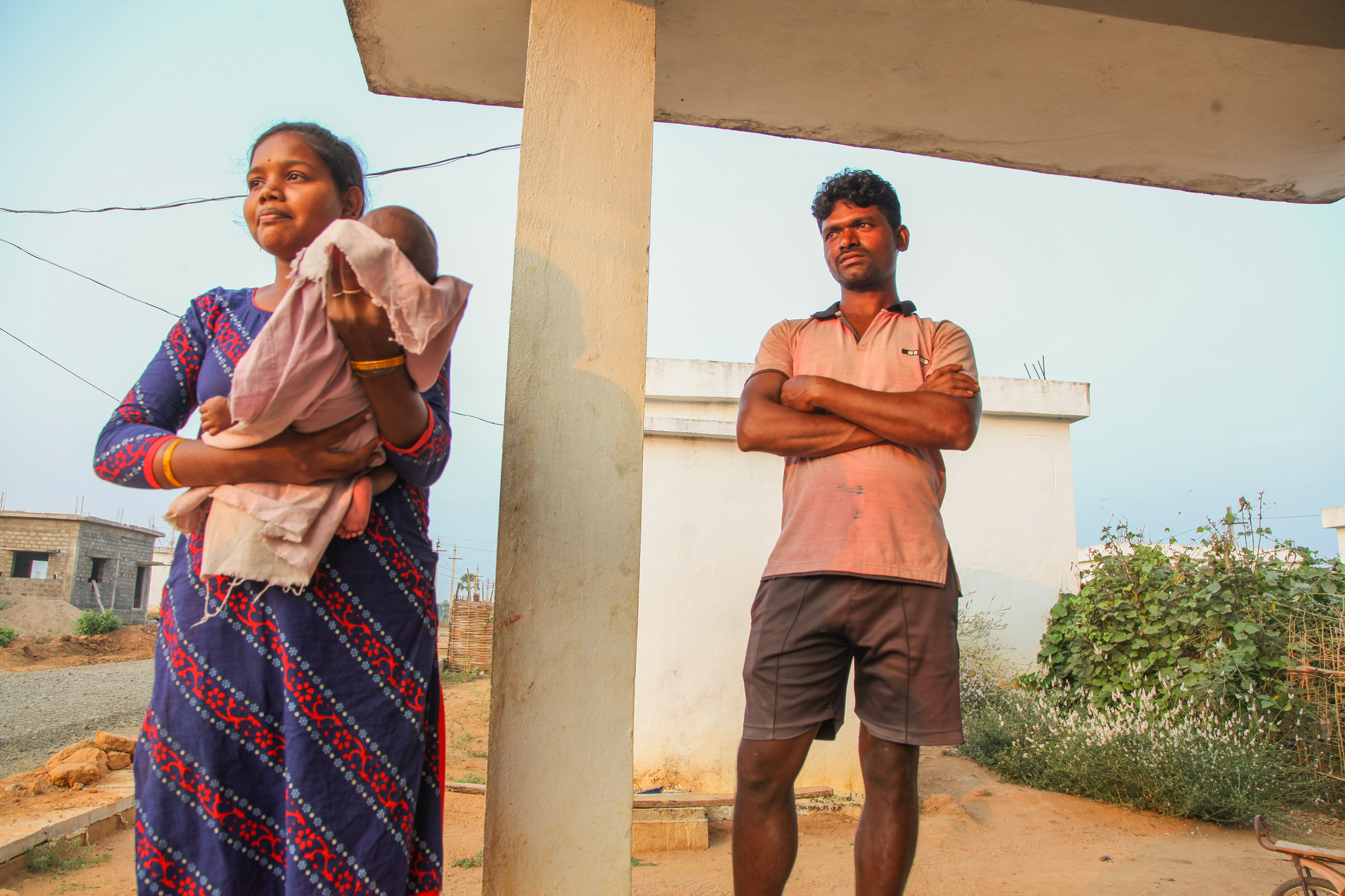 Young mum holding baby with man next to crossed arm