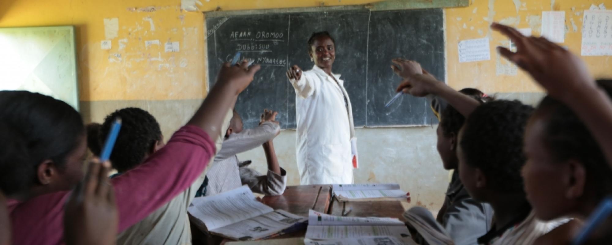 teacher in a white lab coat at a blackboard 