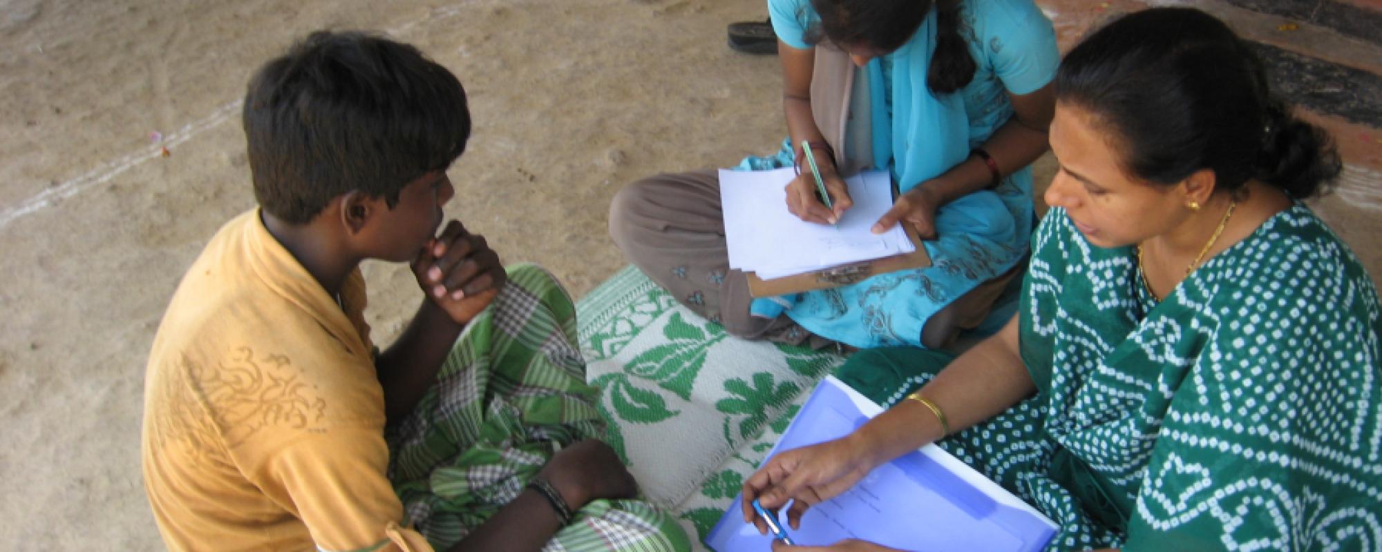 teenagers sat on the floor with their mother doing homework 