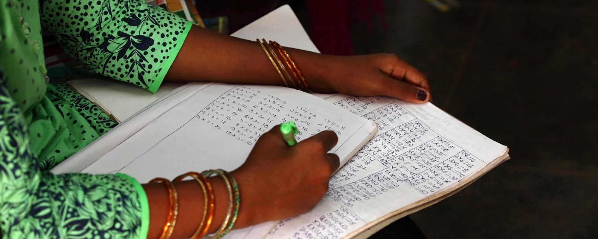 women writing out sums in a notebook