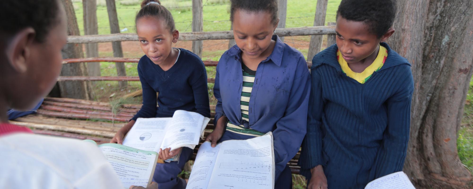 school girls looking at their books outside