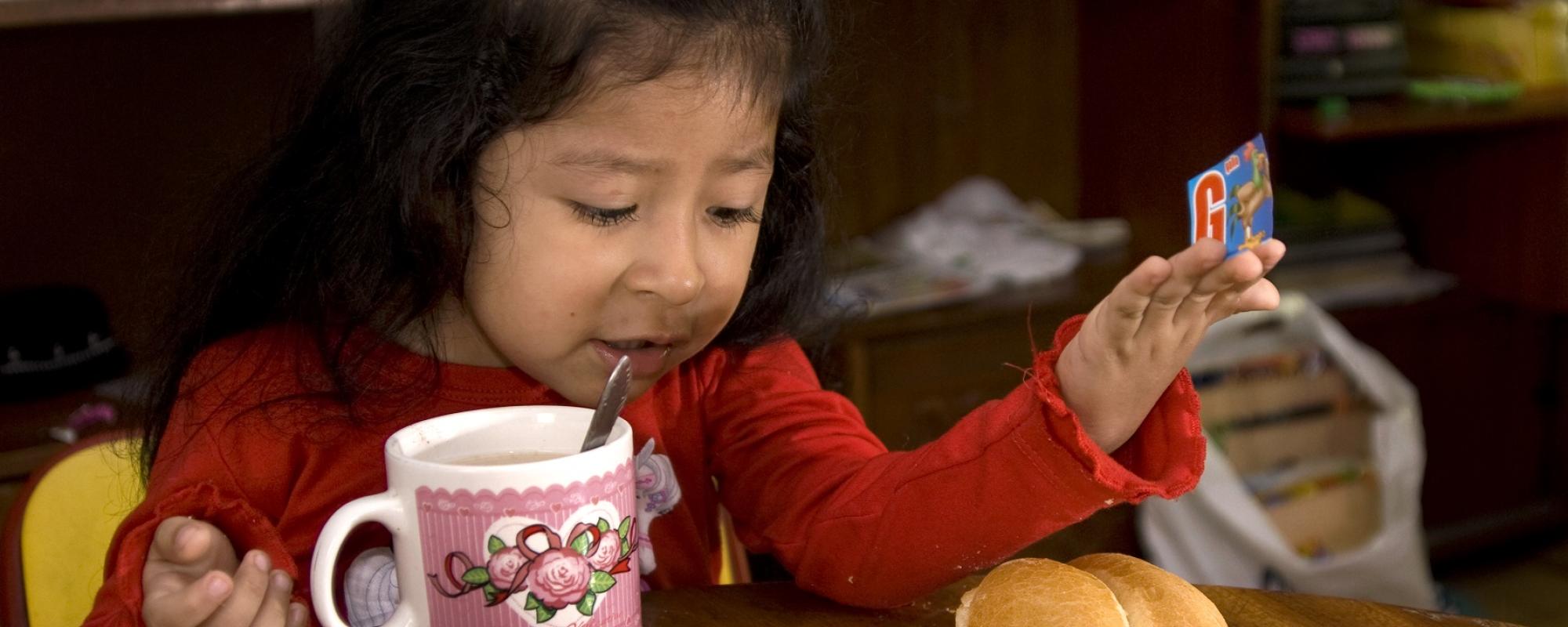 girl eating at a table playing with cards