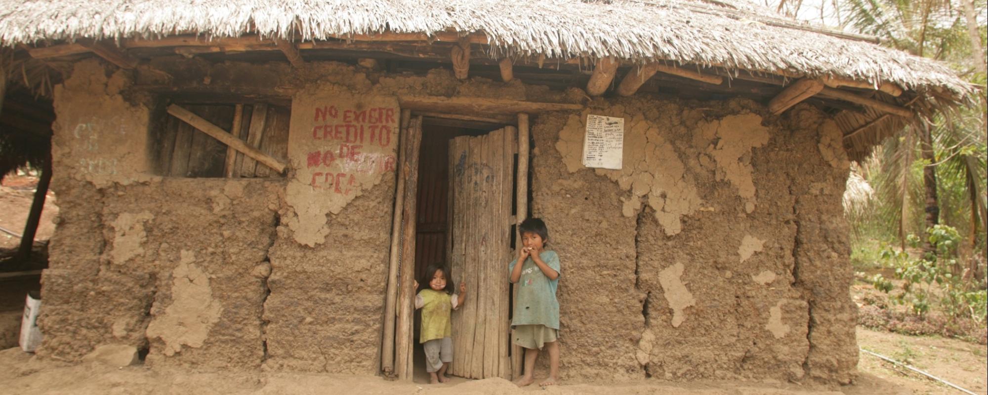 children standing outside mud house