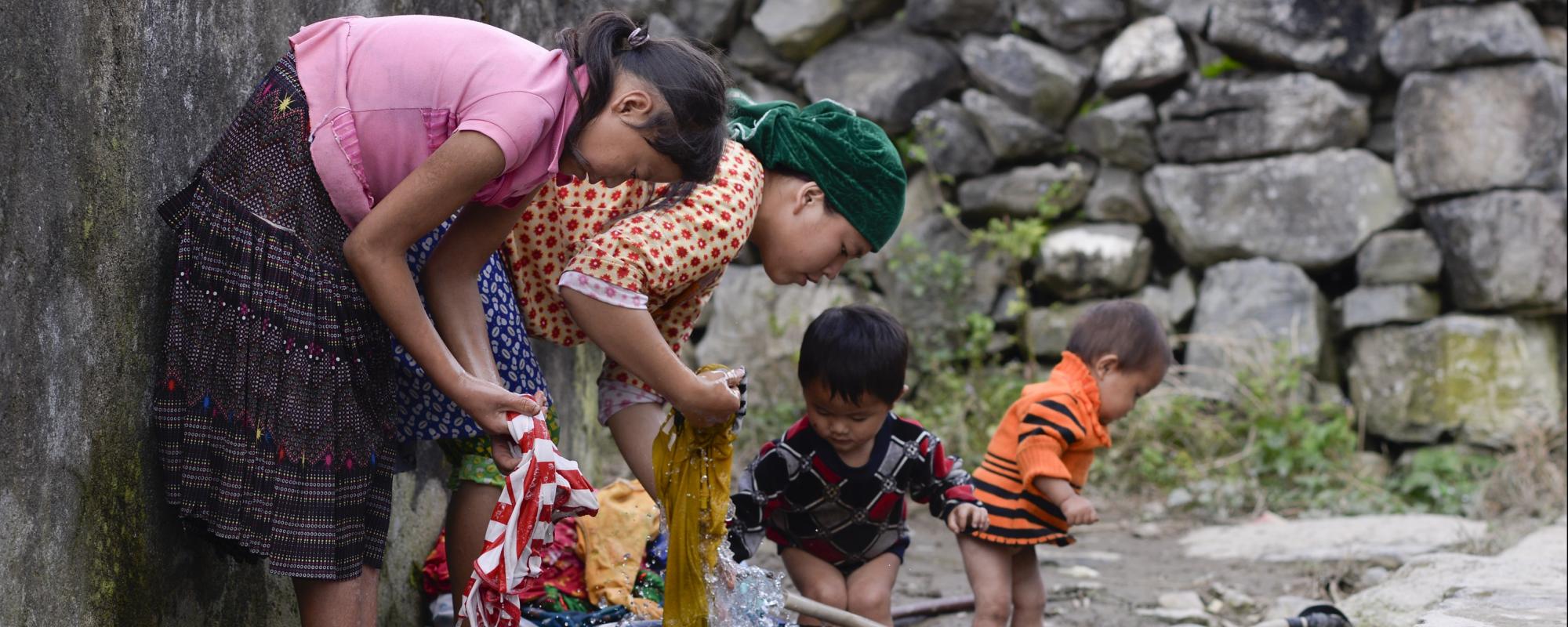 Mum with three young children handwashing clothes