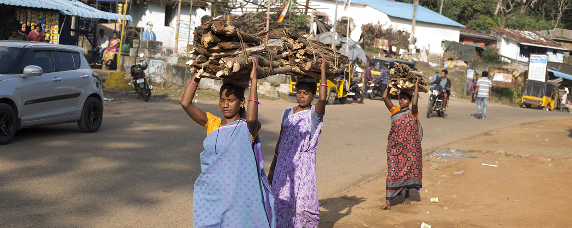 Three women carrying logs