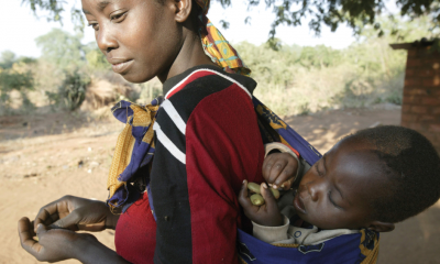 women carrying her baby in a sling on her back