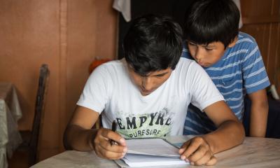 Two boys hunches over a book reading