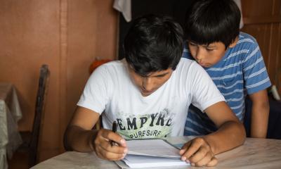 Two boys hunches over a book reading 