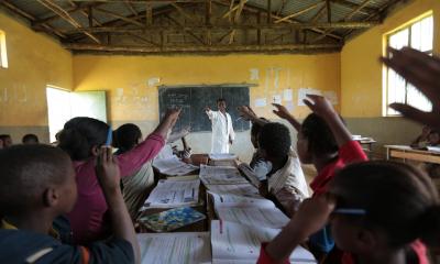 classroom of students with their hands up 