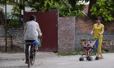 man on a bike and a women with a pram passing one another in the stret