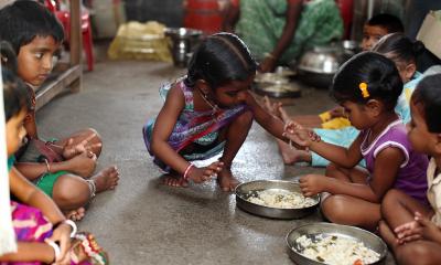 Small girls crouched on the floor eating rice