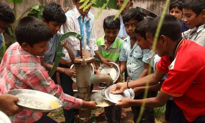 children washing plates at a water pump