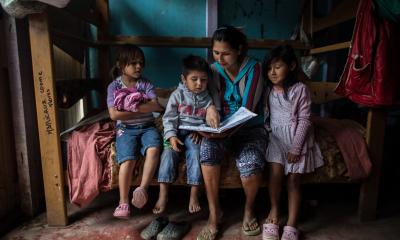 A mother and her children sat on a bed reading 