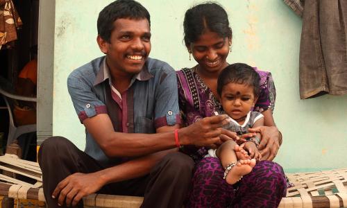 a father, mother and baby sitting together