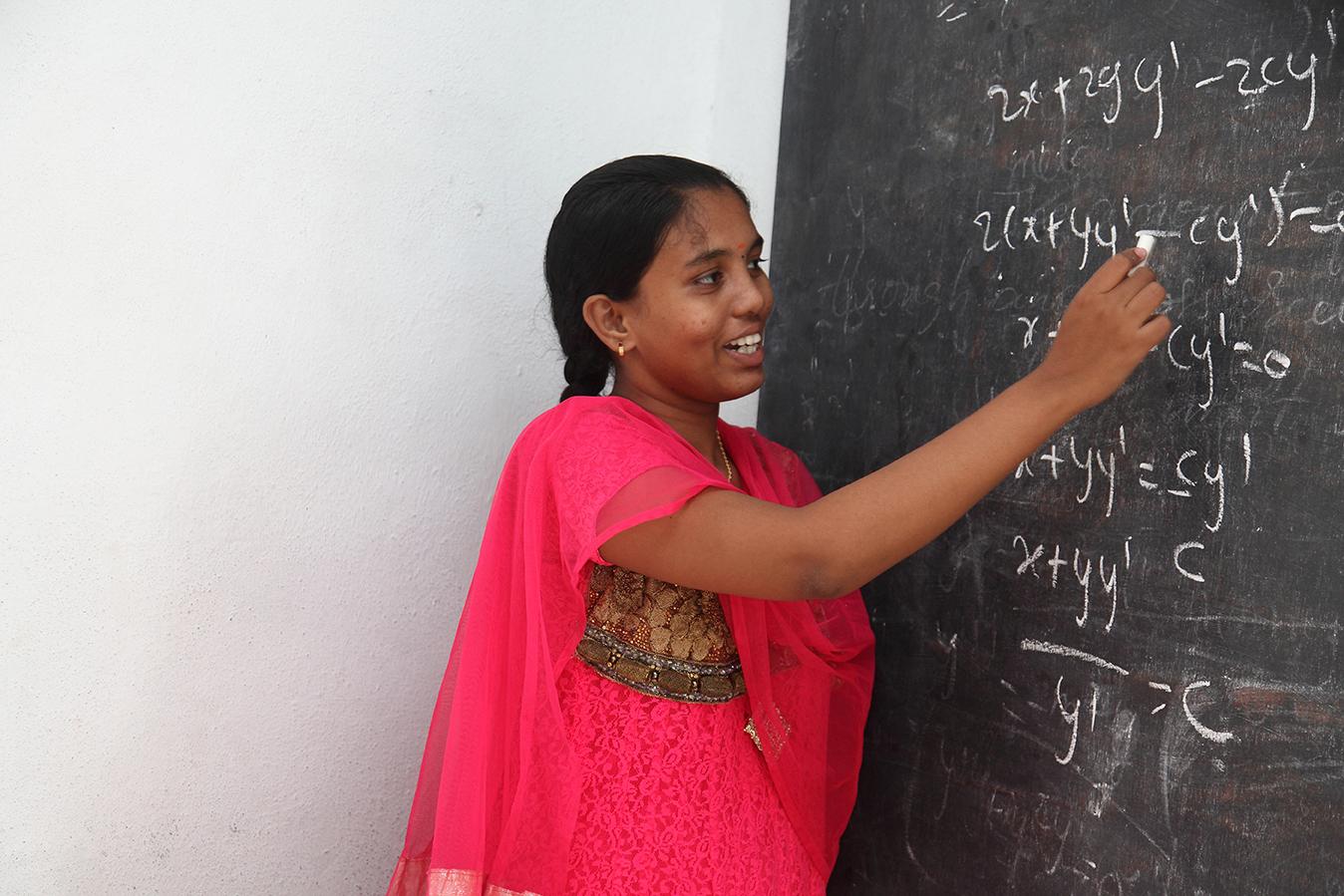 women in pink writing on a blackboard 