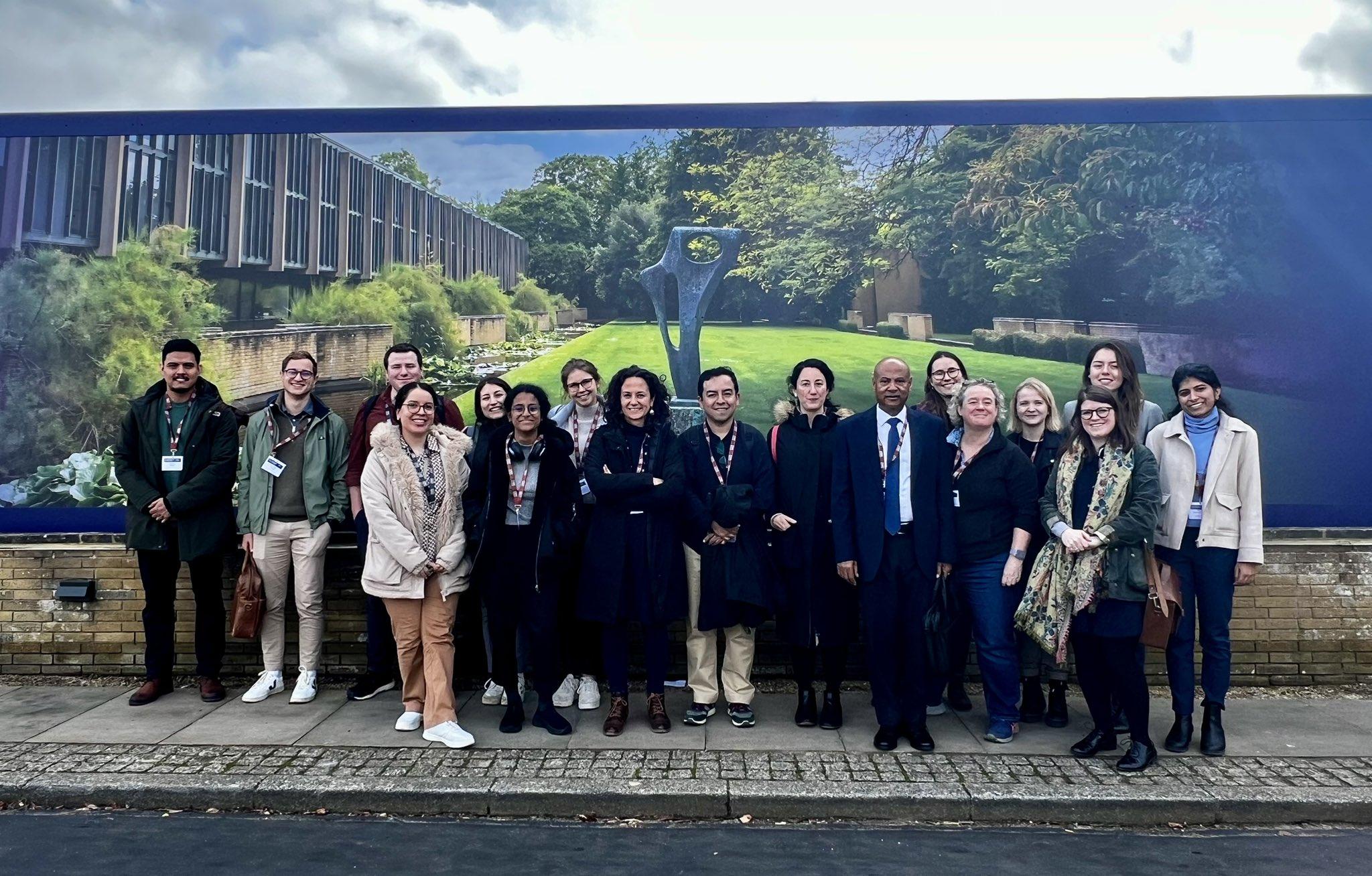 A group of 17 Young Lives researchers stood outside, in front of a wall at the CSAE conference