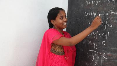 women in pink writing on a blackboard 