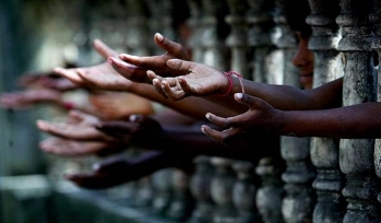 Children hands reaching through a gate