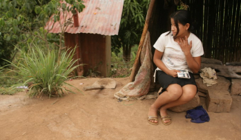 Young Peruvian girl sitting outside her house in the jungle