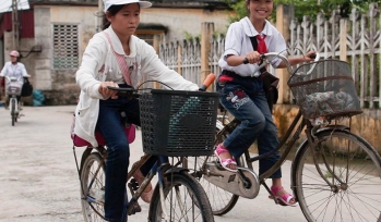 Two girls ride their bikes through town
