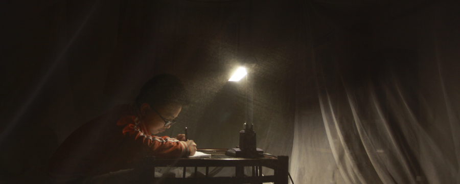 Child writing by candle light